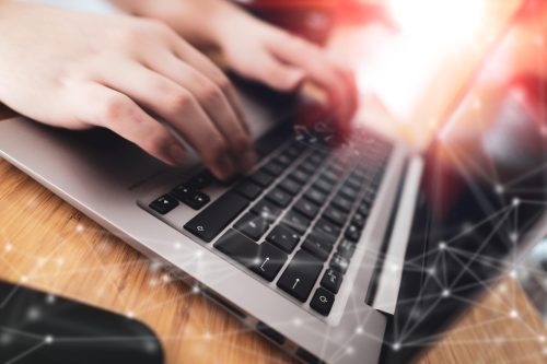 COMPUTER – Person schreibt auf der Tastatur – Graues Notebook auf dem Holztisch COMPUTER - Person schreibt auf der Tastatur - Graues Notebook auf dem Holztisch